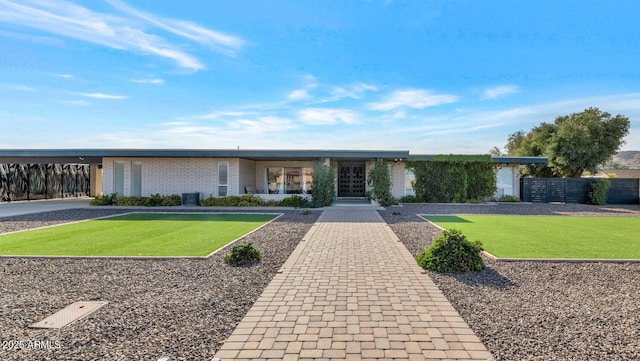 ranch-style home featuring a front lawn and central AC unit