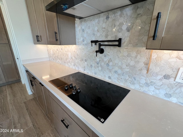 kitchen featuring hardwood / wood-style flooring, tasteful backsplash, custom range hood, and black electric cooktop