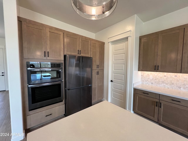 kitchen featuring black fridge, hardwood / wood-style floors, and stainless steel double oven