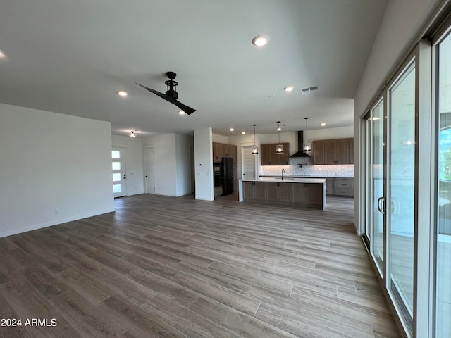 unfurnished living room with sink, ceiling fan, and hardwood / wood-style floors