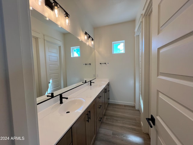 bathroom with vanity with extensive cabinet space, double sink, and wood-type flooring