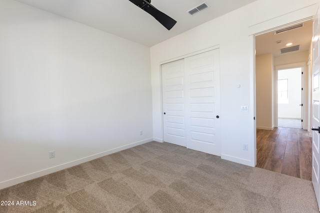 unfurnished bedroom featuring ceiling fan, dark colored carpet, and a closet