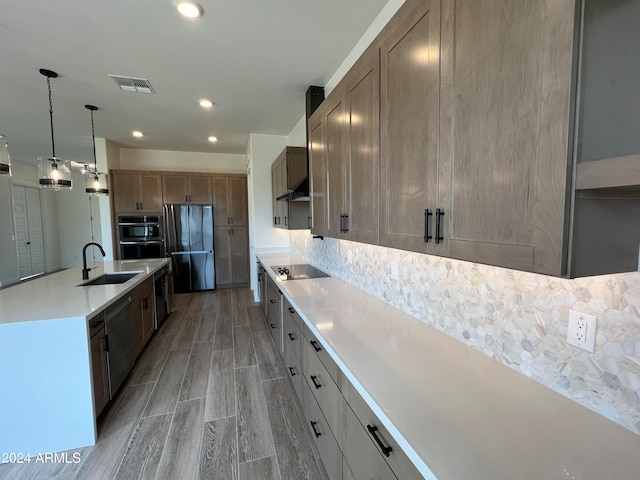 kitchen with black appliances, backsplash, wood-type flooring, pendant lighting, and sink