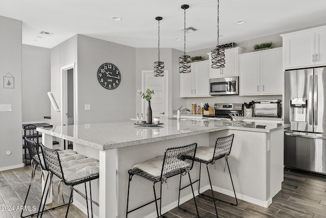 kitchen with white cabinets, a center island with sink, appliances with stainless steel finishes, and dark hardwood / wood-style flooring