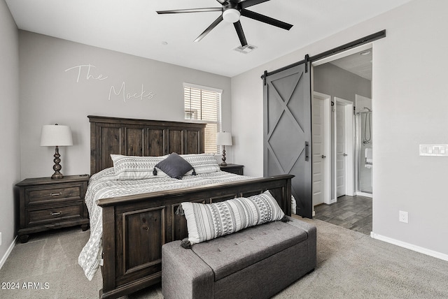 bedroom with ceiling fan, a barn door, connected bathroom, and carpet flooring