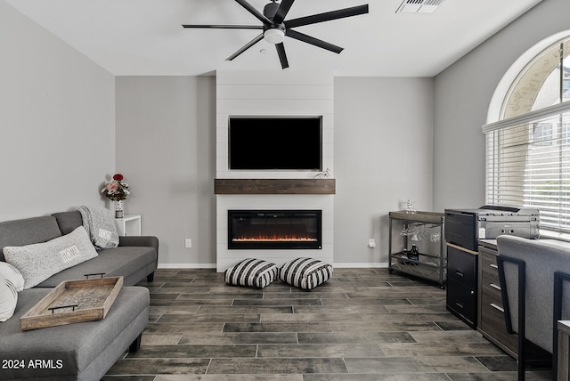 living room featuring a large fireplace, plenty of natural light, dark hardwood / wood-style flooring, and ceiling fan