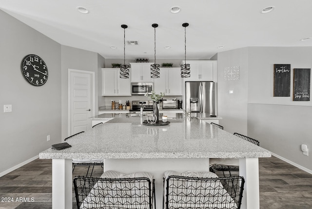 kitchen featuring a spacious island, white cabinets, stainless steel appliances, and a kitchen bar