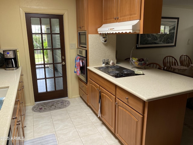 6637 E Culver St, Scottsdale, AZ 85257 - kitchen with under cabinet range hood, black electric cooktop, built in microwave, stainless steel oven, and light tile patterned floors