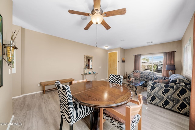 dining space with ceiling fan and light hardwood / wood-style flooring