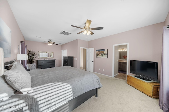 bedroom featuring ensuite bathroom, light colored carpet, and ceiling fan