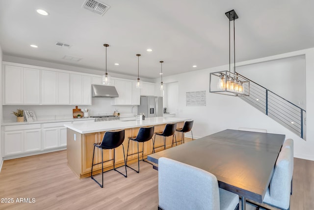 3592 W Cobalt Ct, San Tan Valley, AZ 85144 - kitchen featuring under cabinet range hood, stainless steel fridge, light wood-style floors, white cabinetry, and light countertops