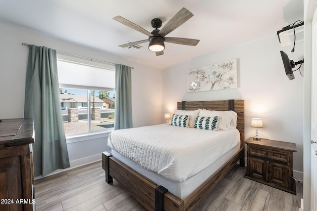 bedroom with light wood-type flooring, crown molding, and ceiling fan