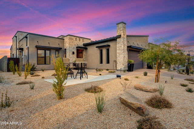 back house at dusk featuring a patio