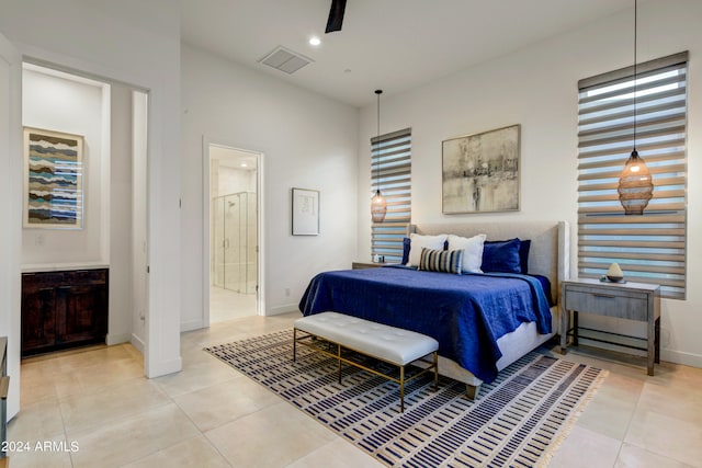 bedroom featuring ceiling fan, light tile patterned floors, and ensuite bath