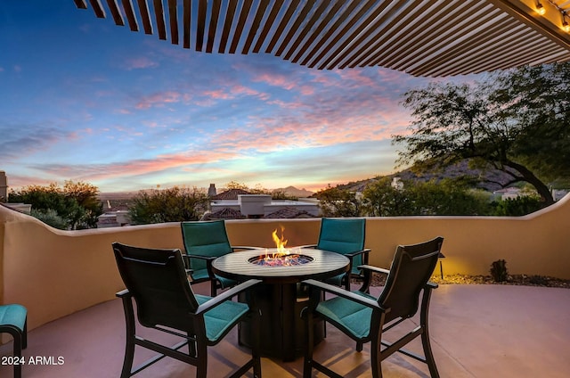 balcony at dusk featuring a patio area and a fire pit