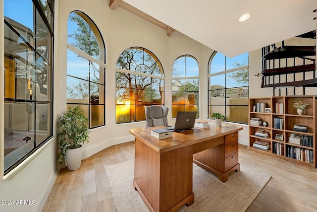 office area featuring beam ceiling, a healthy amount of sunlight, and light hardwood / wood-style floors