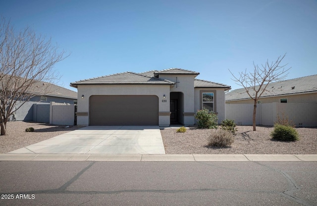 view of front of house with stucco siding, fence, concrete driveway, an attached garage, and a tiled roof