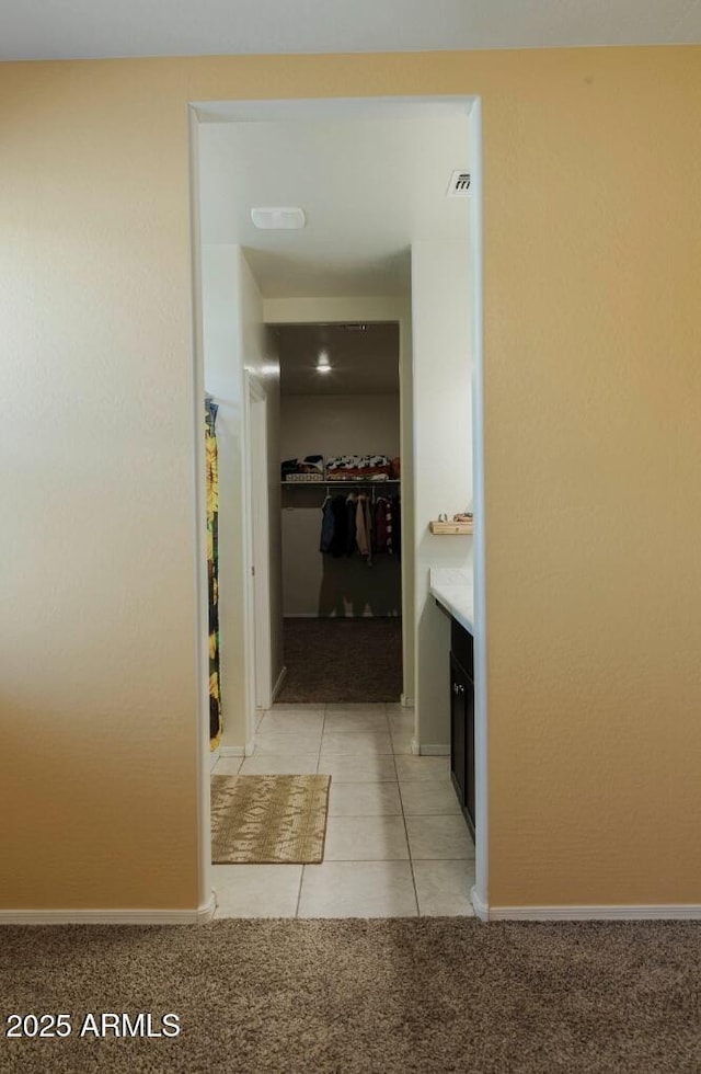 bathroom featuring visible vents, a walk in closet, baseboards, tile patterned floors, and vanity