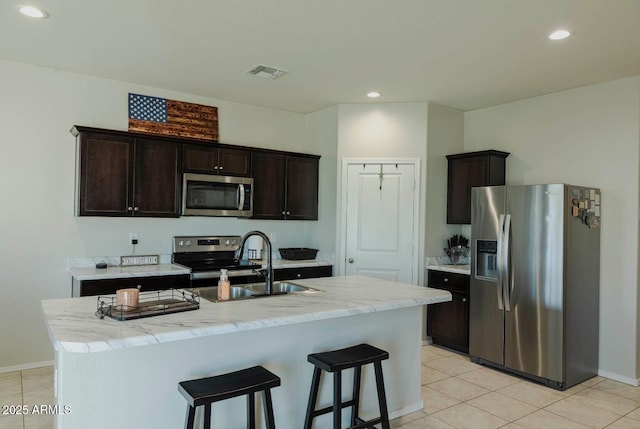 kitchen featuring visible vents, dark brown cabinets, a breakfast bar, appliances with stainless steel finishes, and a sink