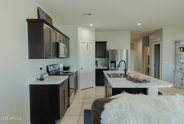 kitchen with visible vents, a sink, light tile patterned flooring, stainless steel appliances, and a kitchen island with sink