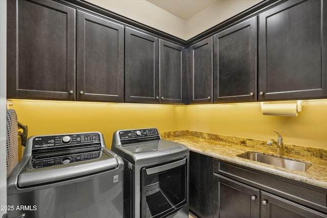 clothes washing area with a sink, cabinet space, and washer and dryer