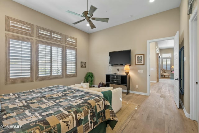 bedroom featuring baseboards, light wood-style floors, and a ceiling fan