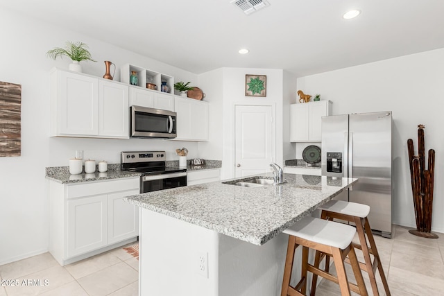 kitchen featuring stainless steel appliances, sink, an island with sink, and white cabinets