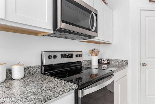 kitchen with tile patterned flooring, appliances with stainless steel finishes, white cabinets, and light stone counters