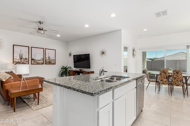 kitchen with sink, dishwasher, a kitchen island with sink, dark stone countertops, and white cabinets