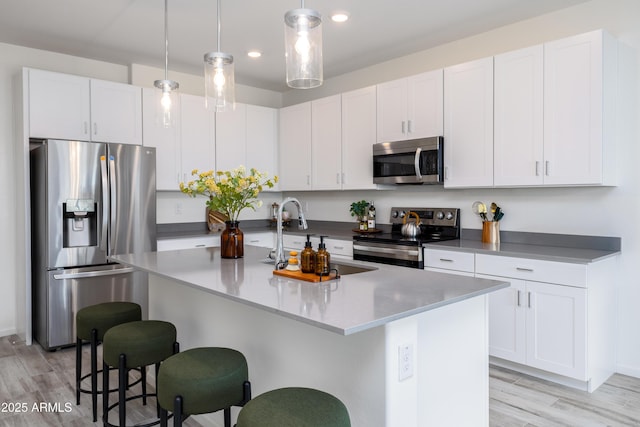 kitchen with sink, stainless steel appliances, an island with sink, and white cabinets