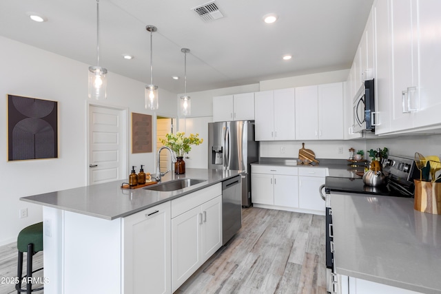 kitchen featuring a kitchen island with sink, stainless steel appliances, and white cabinets