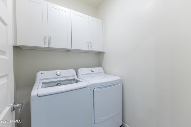 clothes washing area featuring cabinets and washer and clothes dryer