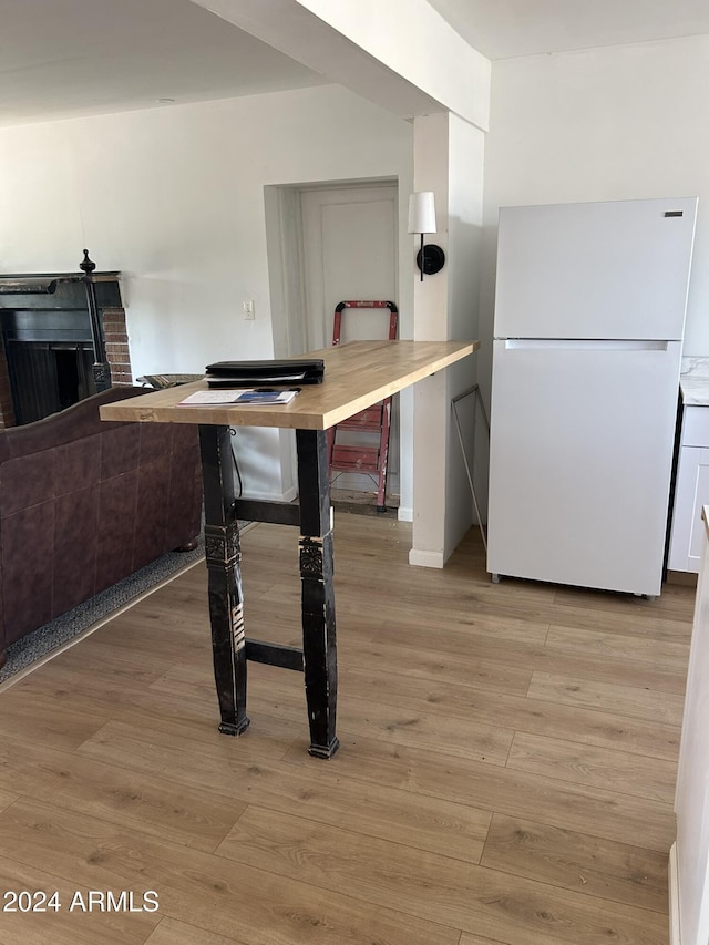 kitchen featuring a fireplace, light wood-type flooring, and freestanding refrigerator