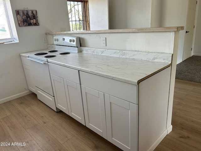 kitchen featuring plenty of natural light, light wood-style floors, white cabinets, and electric stove