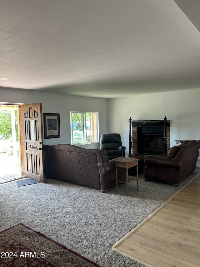 living room with a brick fireplace and wood finished floors