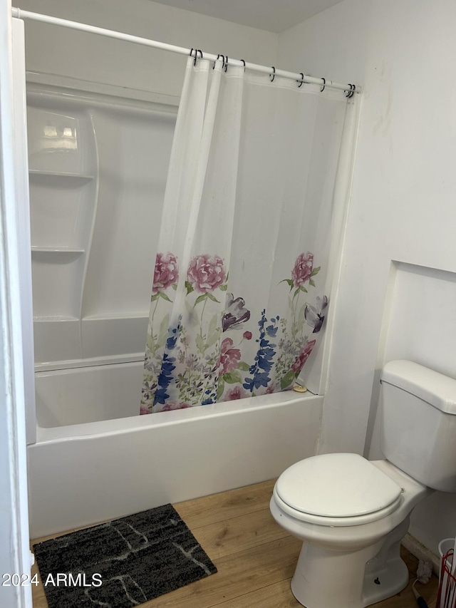 bathroom with shower / tub combo, toilet, and wood finished floors