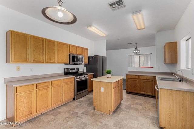 kitchen featuring light countertops, a kitchen island, a sink, visible vents, and appliances with stainless steel finishes