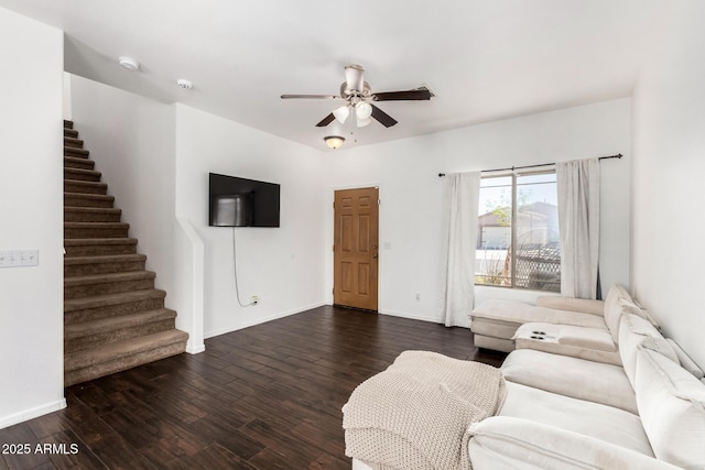 unfurnished living room featuring a ceiling fan, dark wood-style flooring, baseboards, and stairway