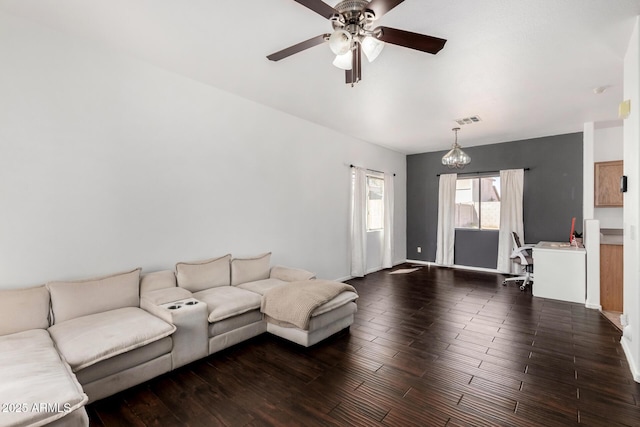 living area featuring dark wood-style flooring, visible vents, and ceiling fan with notable chandelier