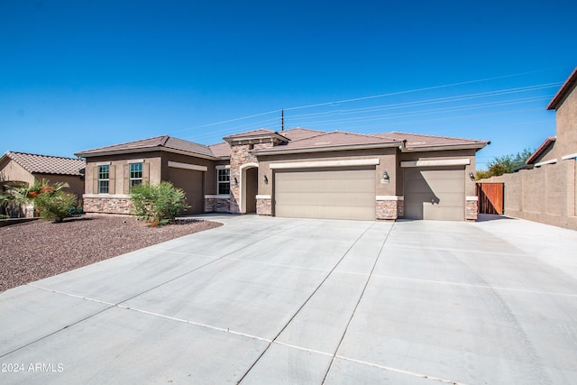 prairie-style house with stone siding, stucco siding, and an attached garage