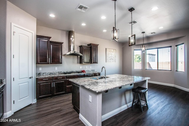 kitchen featuring a sink, stainless steel gas cooktop, visible vents, and wall chimney exhaust hood