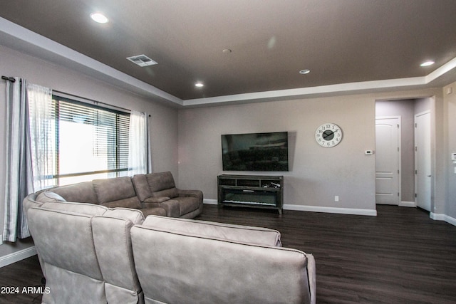 living room featuring dark wood-style floors, a tray ceiling, baseboards, and visible vents