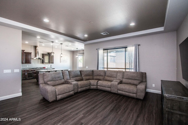 living room with dark wood-style flooring, a tray ceiling, and visible vents