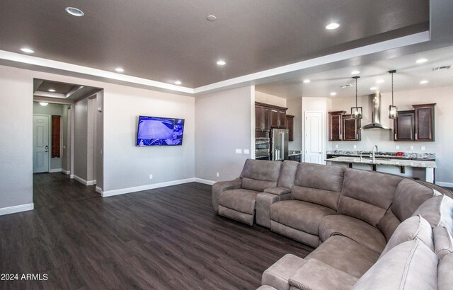 living room with a raised ceiling, sink, and dark hardwood / wood-style flooring