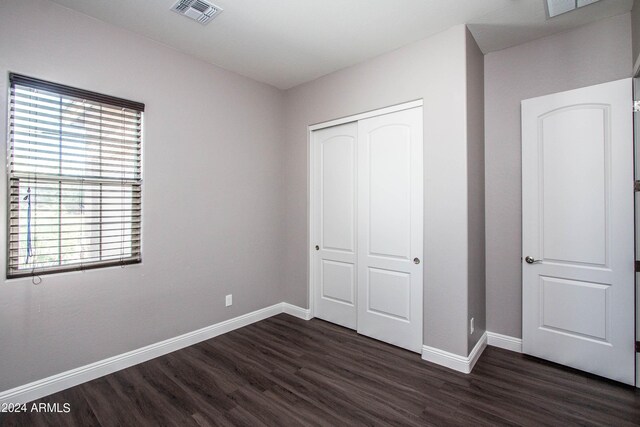 unfurnished bedroom featuring a closet and dark hardwood / wood-style flooring