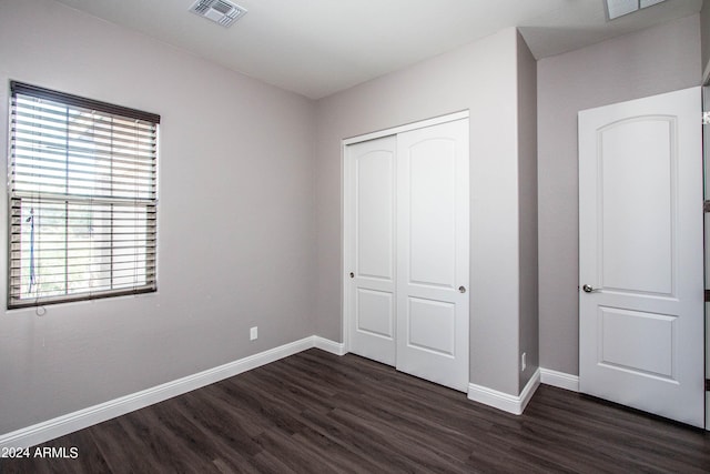 unfurnished bedroom with baseboards, visible vents, a closet, and dark wood-style floors