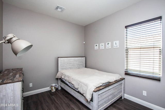 bedroom featuring baseboards, visible vents, multiple windows, and wood finished floors