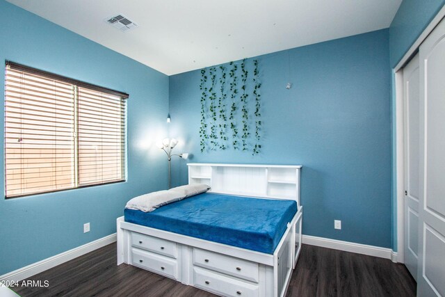 bedroom with dark hardwood / wood-style floors and a closet