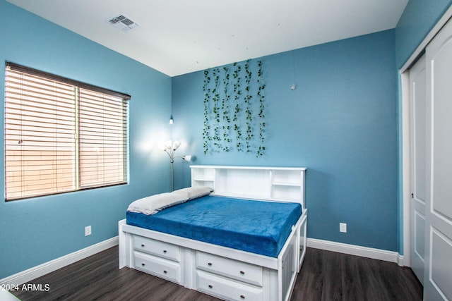 bedroom with dark wood finished floors, a closet, baseboards, and visible vents