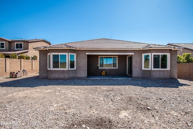 rear view of property with a fenced backyard, stucco siding, a patio area, and a tiled roof